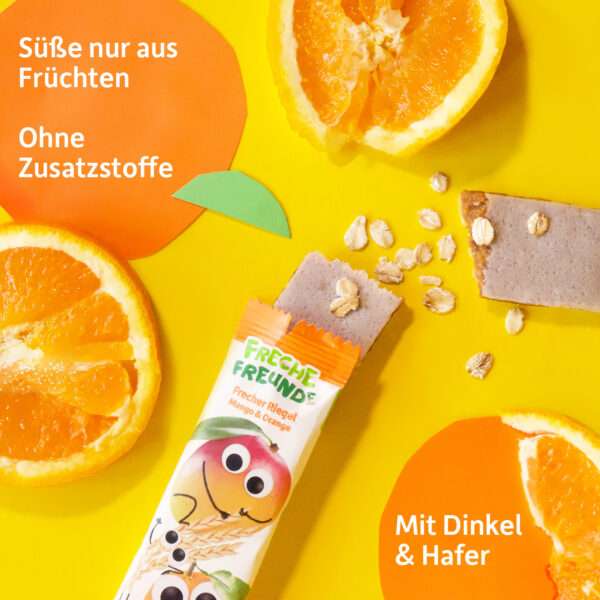 Geöffneter Freche Freunde Bio Riegel Mango & Orange auf gelbem Untergrund, umgeben von Orangenscheiben, Haferflocken und dem Claim: „Süße nur aus Früchten – ohne Zusatzstoffe“. Ein Blick ins Innere des Riegels zeigt die ballaststoffreiche Dinkel-Hafer-Mischung.