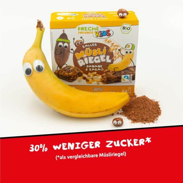 Neben der Verpackung von Freche Freunde Bio Kalles Müsli Riegel Banane & Kakao liegt eine echte Banane mit Kulleraugen. Daneben: eine Portion Kakaopulver und eine Haselnuss. Text: Mit 30 % weniger Zucker als vergleichbare Müsli-Riegel.
