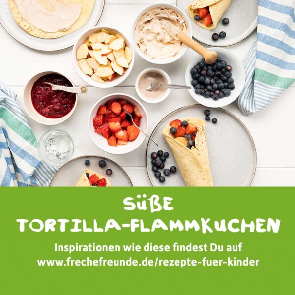 Rezeptidee für süße Flammkuchen-Tortillas von Freche Freunde: Auf einem Tisch liegen frische Zutaten wie Apfelstücke, Erdbeeren, Heidelbeeren, Fruchtpüree, Zimt-Zucker, Quark und Tortillafladen bereit. Die Bildunterschrift zeigt: „Süße Tortilla-Flammkuchen – Inspirationen findest du auf frechefreunde.de/rezepte-fuer-kinder“. Das Bild inspiriert zu kreativen, fruchtigen Snackideen für Kinder.