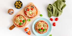 Mini-Kinderpizza-Gesichter mit Tomatennasen, Zucchiniaugen und Pilzmündern