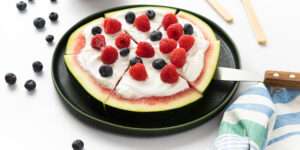 Glutenfreie Kinderpizza: Melonenpizza - Joghurt, Blaubeeren und Himbeeren auf in Sechsteln geteilte Wassermelonenscheibe