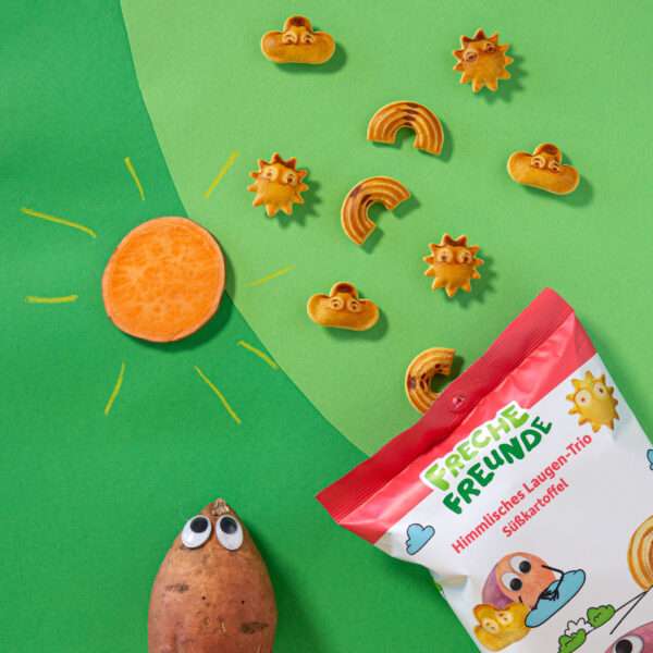 Freche Freunde Himmlisches Laugen-Trio Süßkartoffel auf grünem Hintergrund mit vielen einzelnen Laugen, einer Sonne und Sebastian Süßkartoffel mit Wackelaugen.