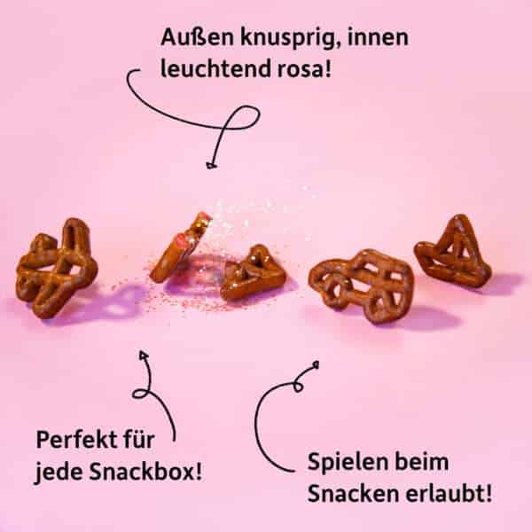 Freche Freunde Bio Laugensnack Rote Bete – Nahaufnahme der kleinen, spielerischen Brezeln in Auto-, Schiff- und Flugzeugform mit rosafarbenem Crunch im Inneren. Dazu Botschaften wie „Spielen beim Snacken erlaubt“ und Perfekt für jede Snackbox.