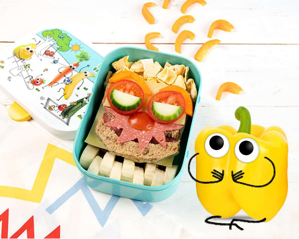 Lunchbox gefüllt mit lustig belegtem Sandwich. Mit Tomate und Gurke sind Augen gelegt und mit einer Salamischeibe mit Zacken geschnitten ein Monstermund.