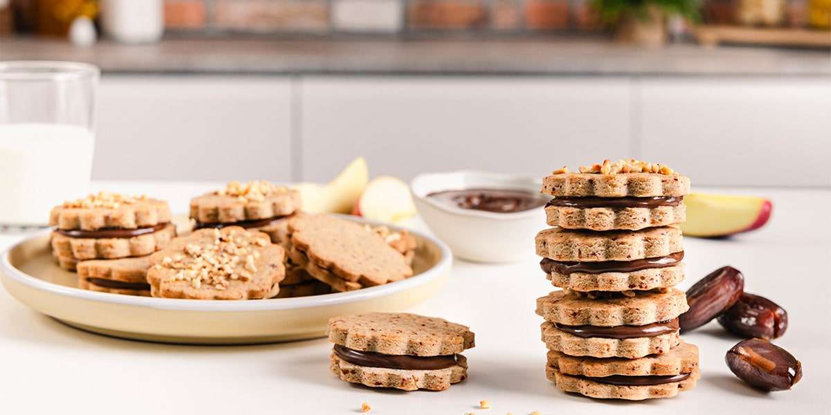Doppelkekse mit Haselnusscreme Füllung auf einem Teller serviert. Rechts steht ein Turm aus Doppelkeksen.