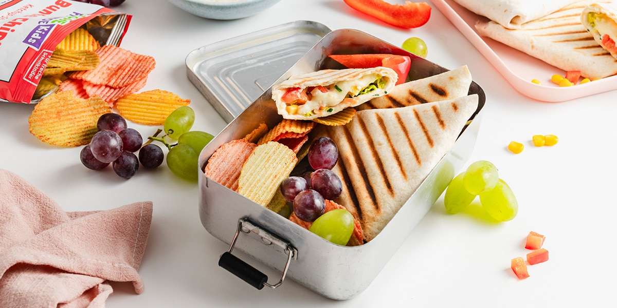 Wrap Taschen in einer Brotdose mit Trauben und Freche Freunde Bunte Chips.