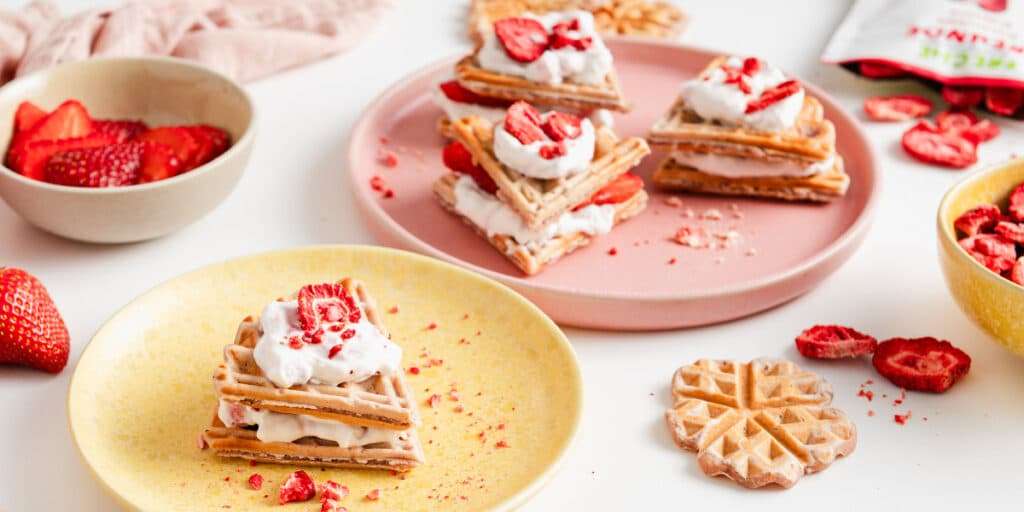 Waffelkuchen mit Erdbeeren auf Tellern serviert. Mit Erdbeer Fruchtchips dekoriert.
